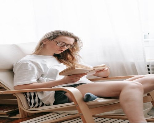 Hombre leyendo un libro en un sillón cómodo con buena postura, relajado en casa